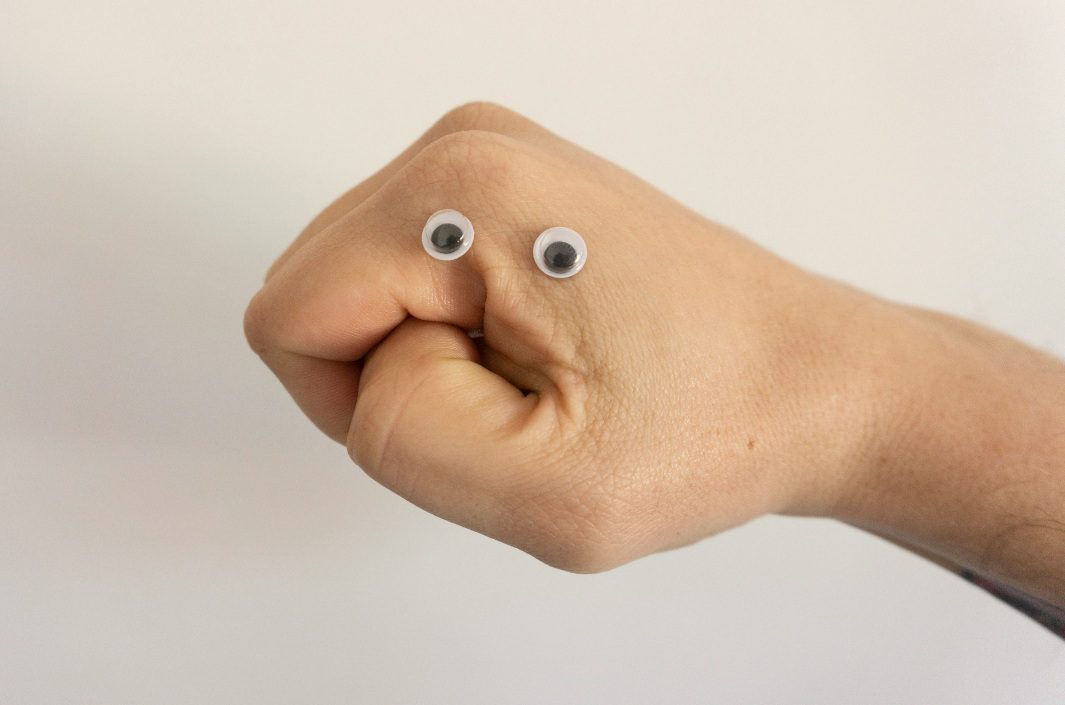 Adult's fist with adhesive wiggly eyes
