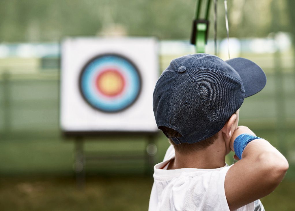 Child taking aim at target with bow and arrow